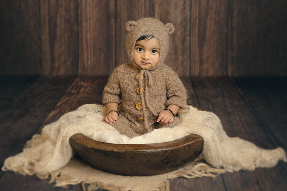 toddler-in-brown-teddy-outfit-in-rustic-bowl-by-surrey-baby-photographer