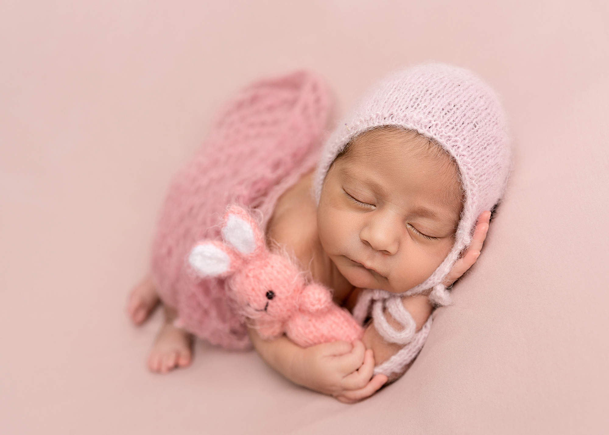 newborn-girl-cuddling-pink-teddy-by-surrey-newborn-baby-photographer