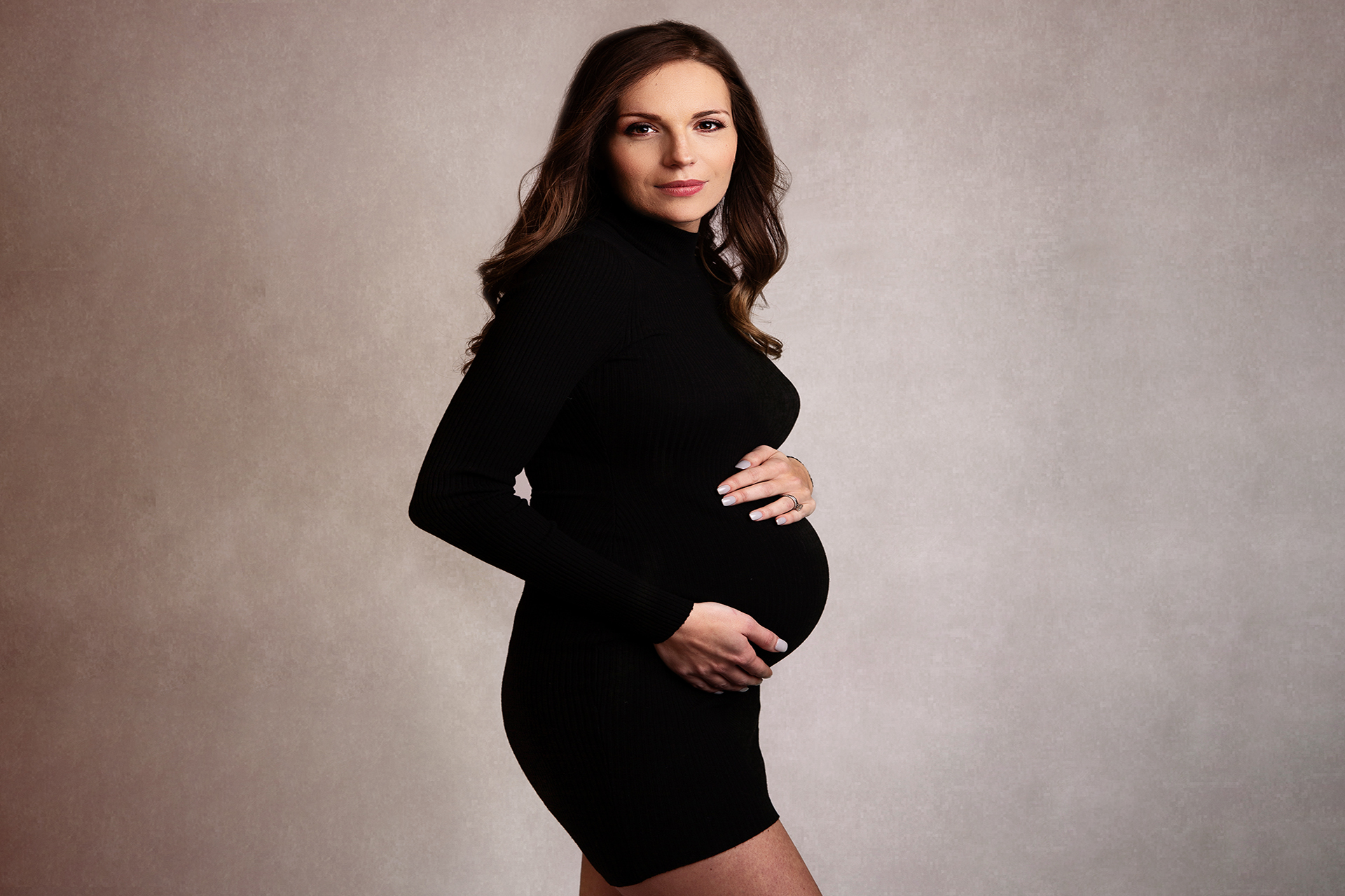 pregnant woman in black maternity dress by surrey maternity photographer